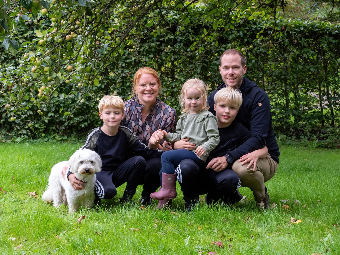 Familien samlet i haven med deres hund